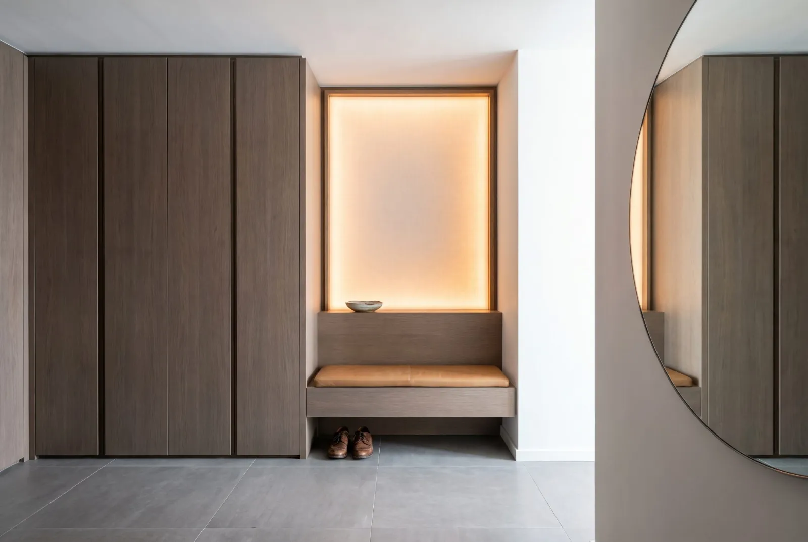An entry wall of smoked oak with a glowing niche and leather bench
