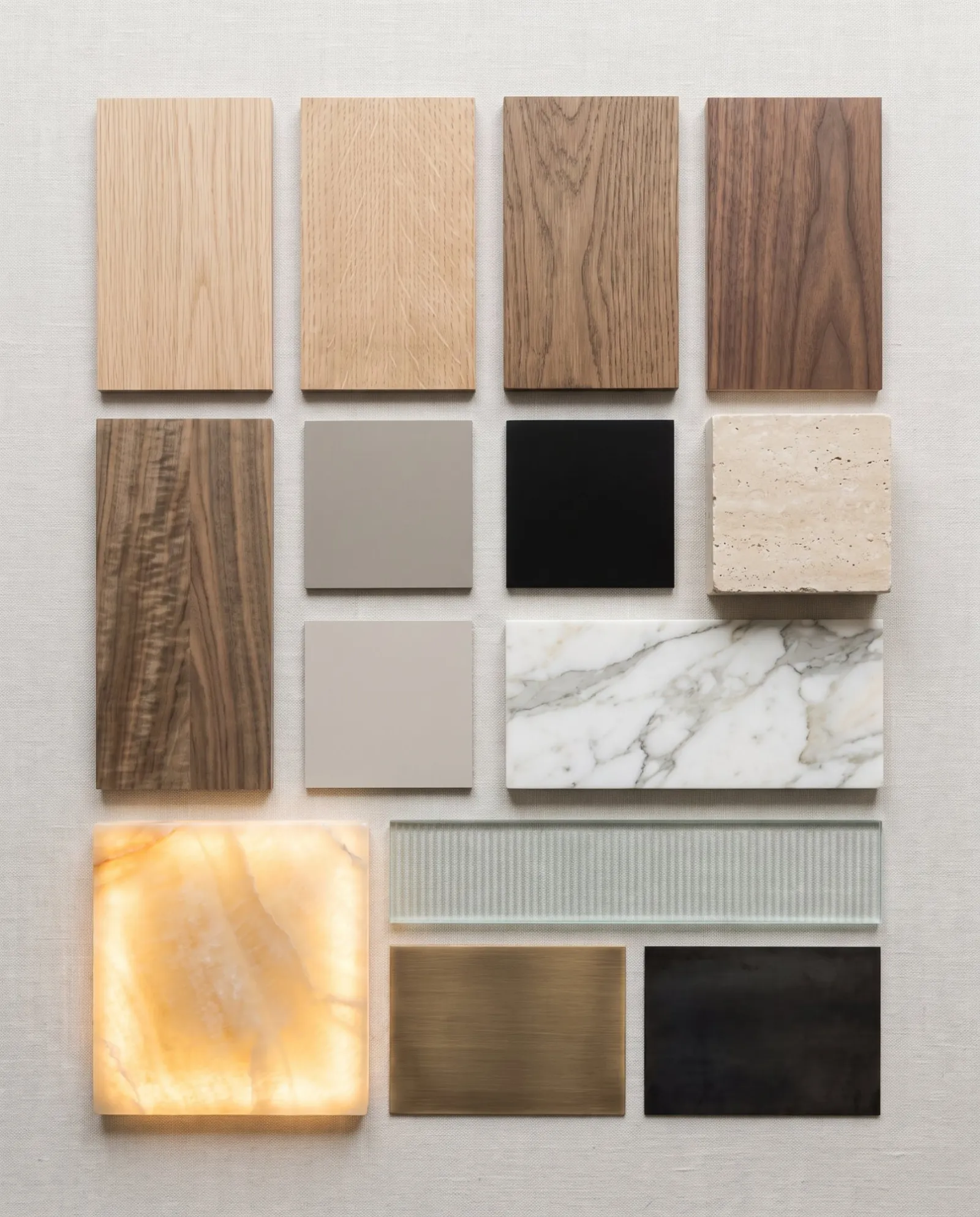 Samples of oak, walnut, travertine, onyx, reeded glass and bronze on a studio table