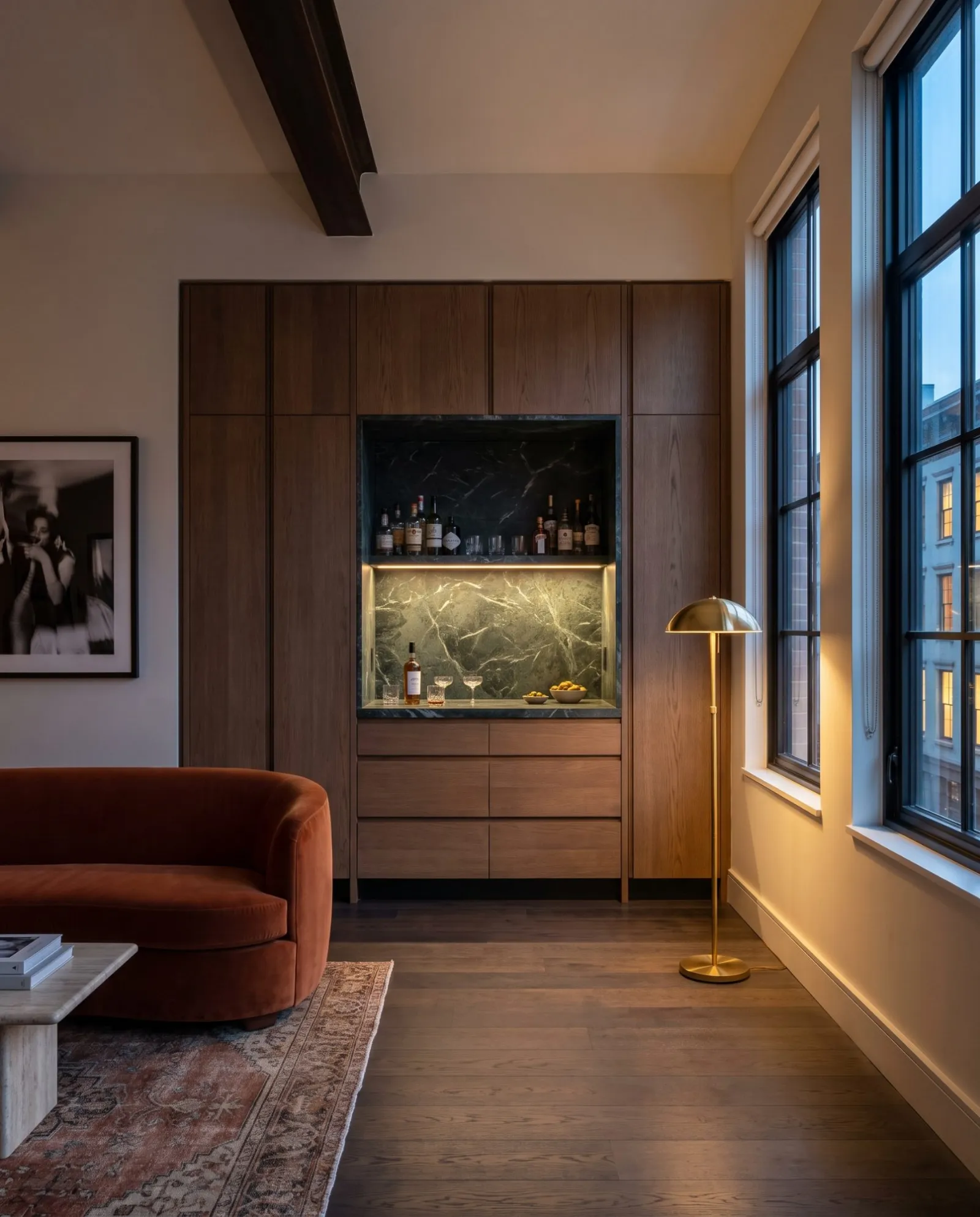 A smoked oak wall with a lit green marble bar niche in a loft